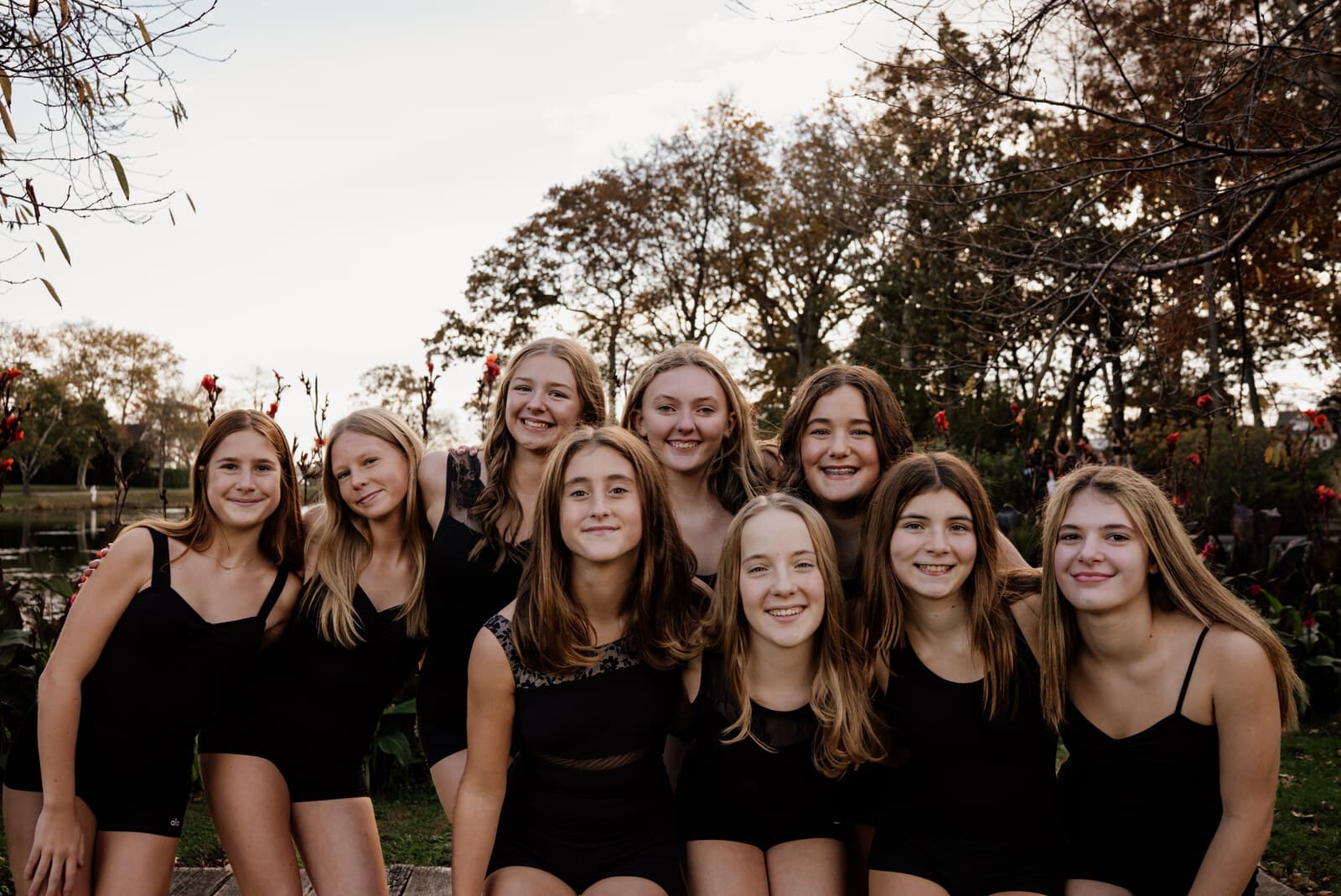 Company dancers smiling together in matching black leotards outdoors