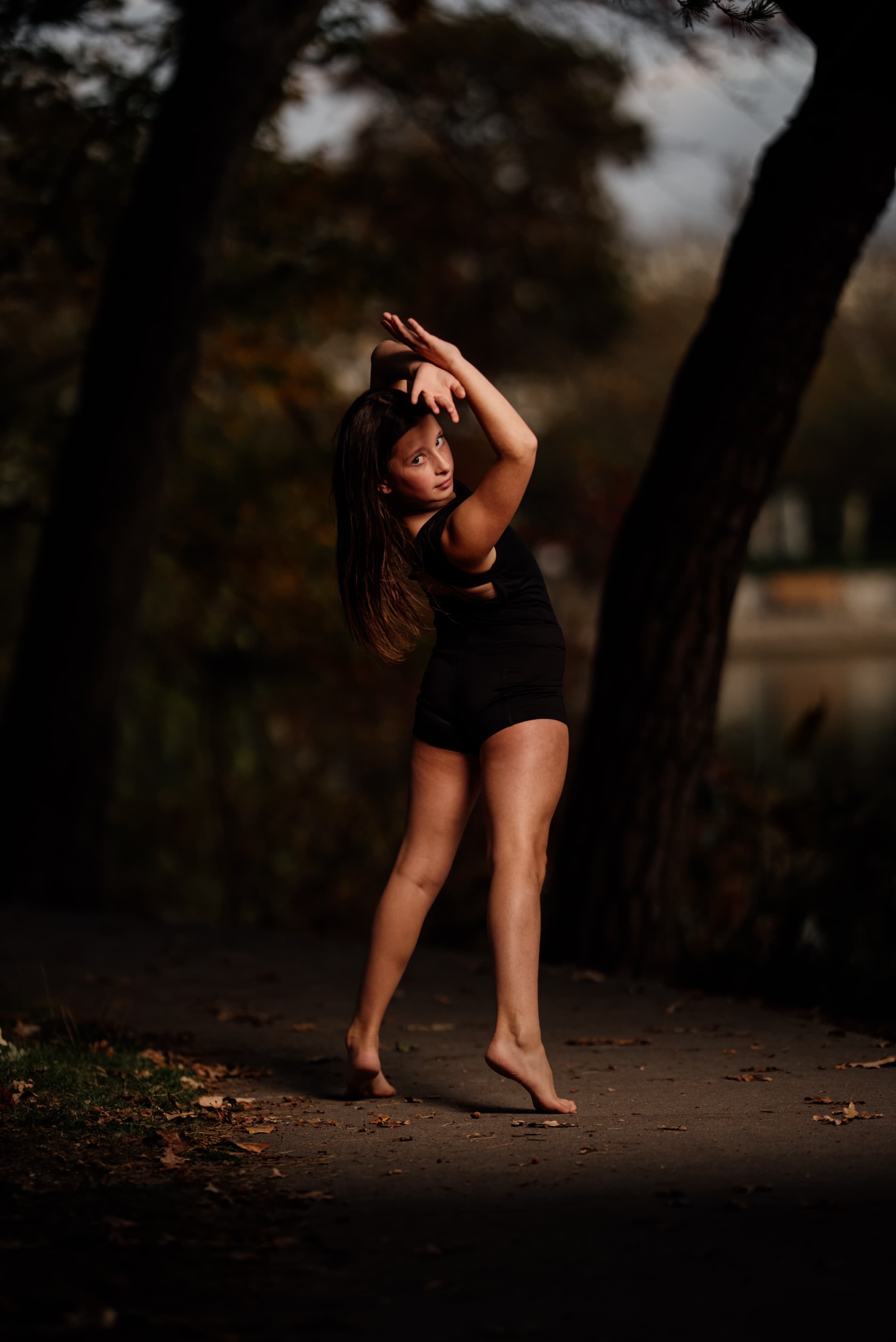 Young dancer striking a graceful pose outdoors at golden hour