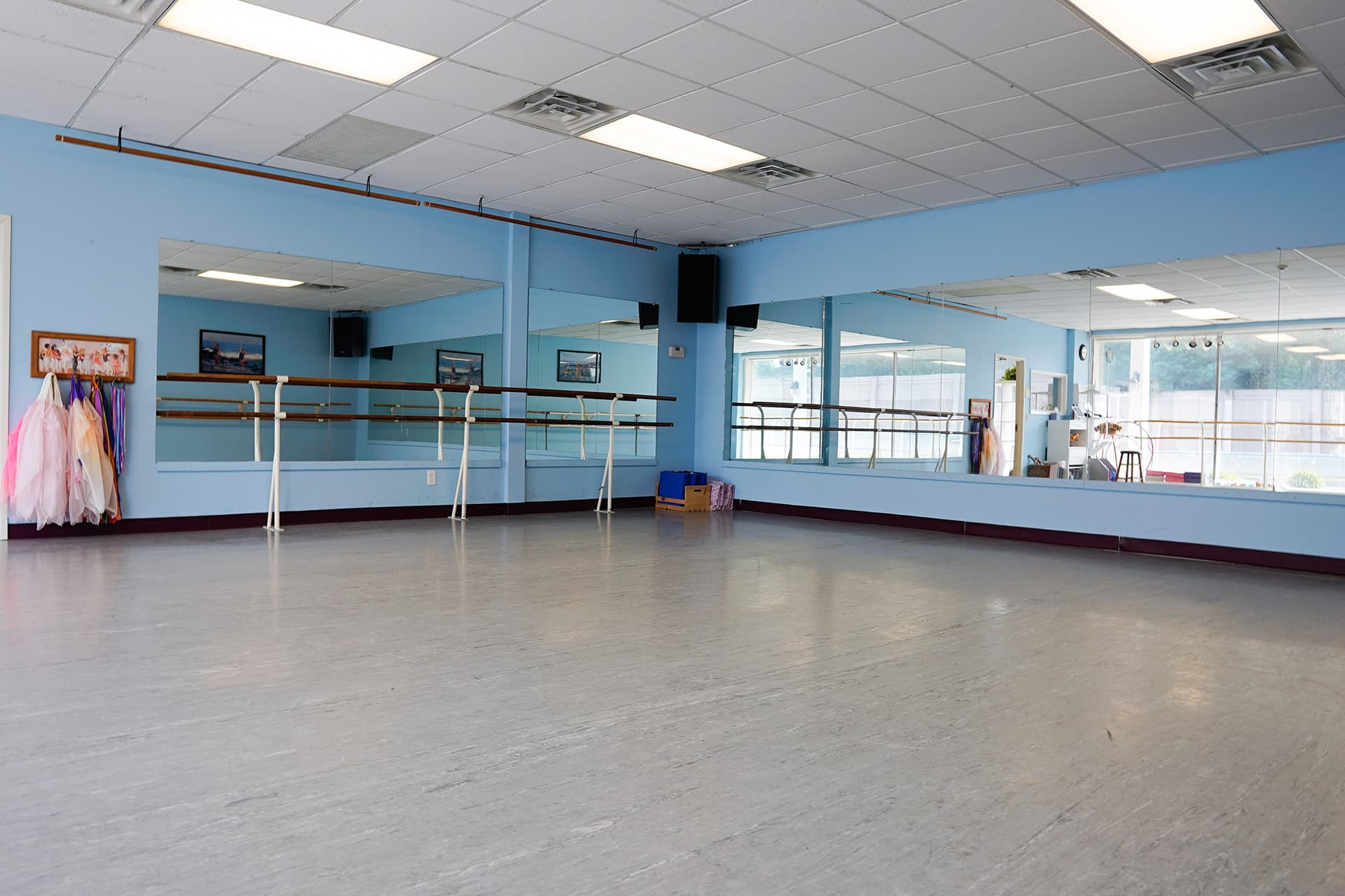 Studio with ballet barre, mirrors, and costumes hanging on the wall