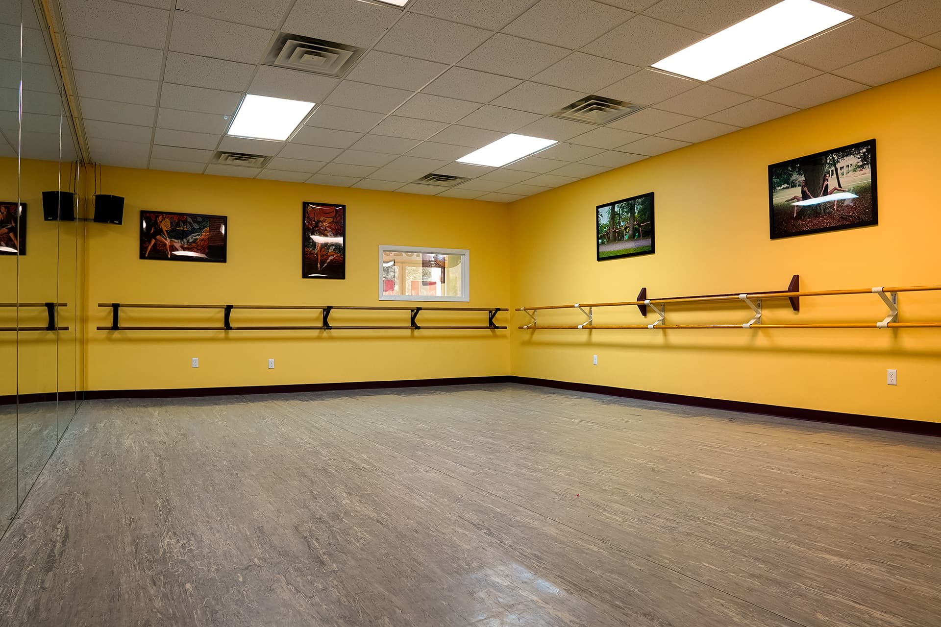 Sunlit yellow studio with barre and framed dance photography